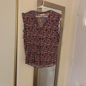 Sleeveless floral blouse with ruffle details! Slight v in neckline.